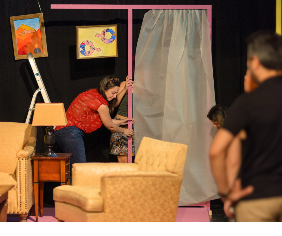 Μαθήτρια σκηνογραφίας στήνει ένα μωβ ξύλινο πλαίσιο ως πλάτη σε υπερυψωμένοο βάθρο.