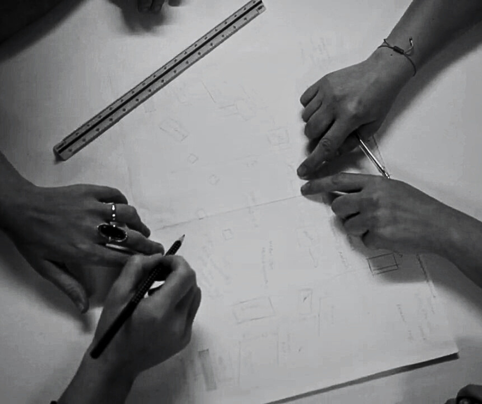 Δύο ζευγάρια χέρια σχεδιάζουν τα σκηνικά κάποιας παράστασης σε χαρτί